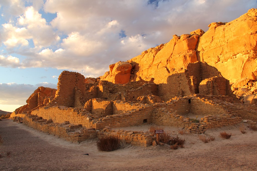Red rock ruins sit under a cloudy sunset at Kin Kletso at Chaco Culture National Historical Park, New Mexico.