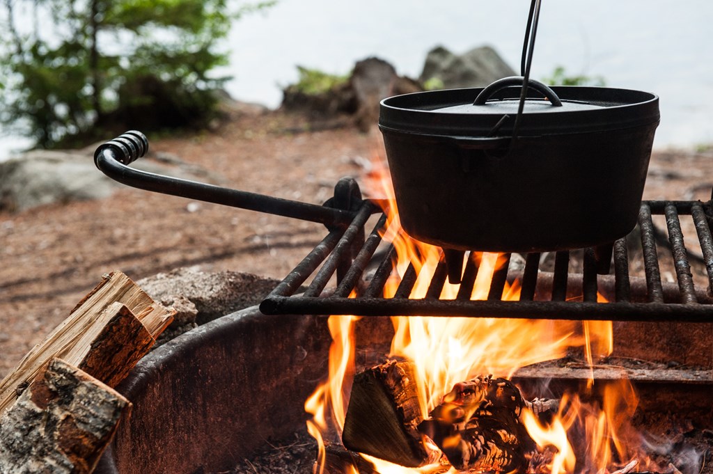 Dutch oven pot cooking over an open campfire.