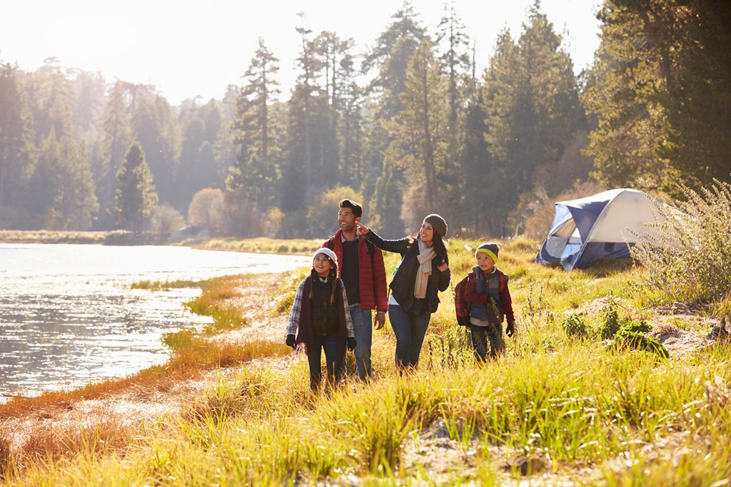 Family on an early spring camping trip takes a walk near a lake.