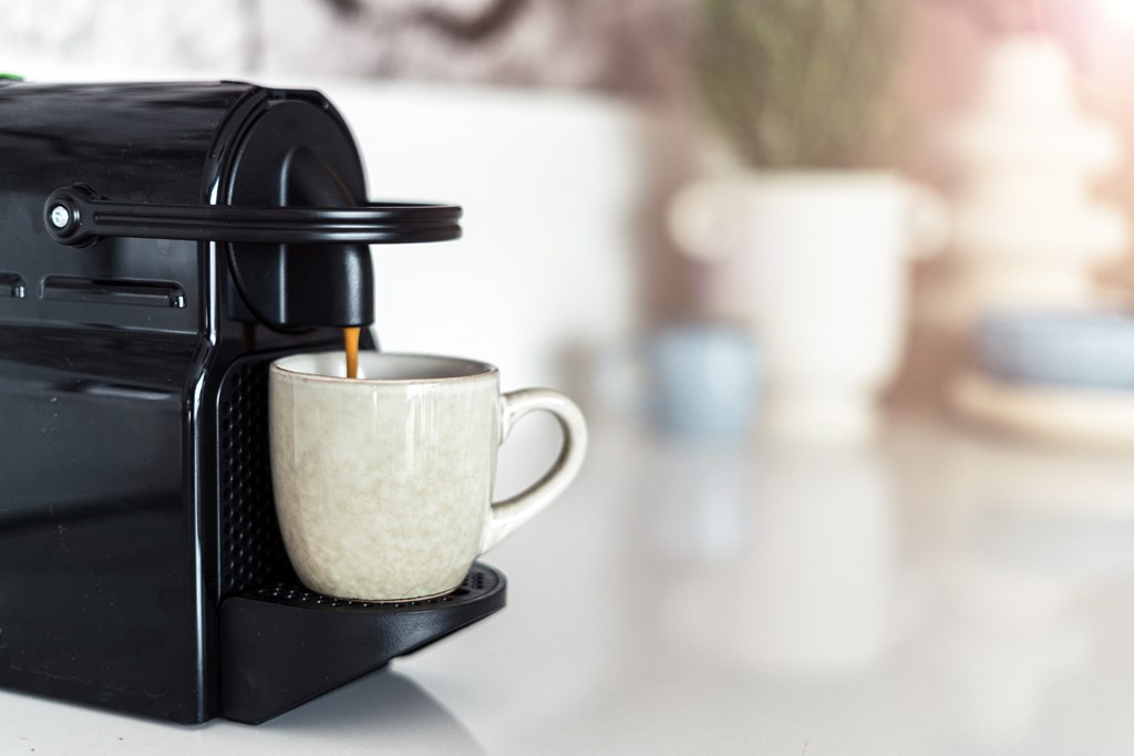 Selective focus on modern coffee machine filling a ceramic mug with espresso.
