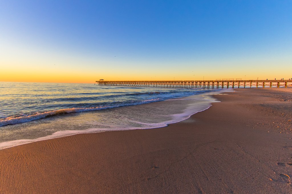 Pier in Myrtle Beach, South Carolina on a wide sandy beach at sunrise in Myrtle Beach along the Atlantic Ocean.